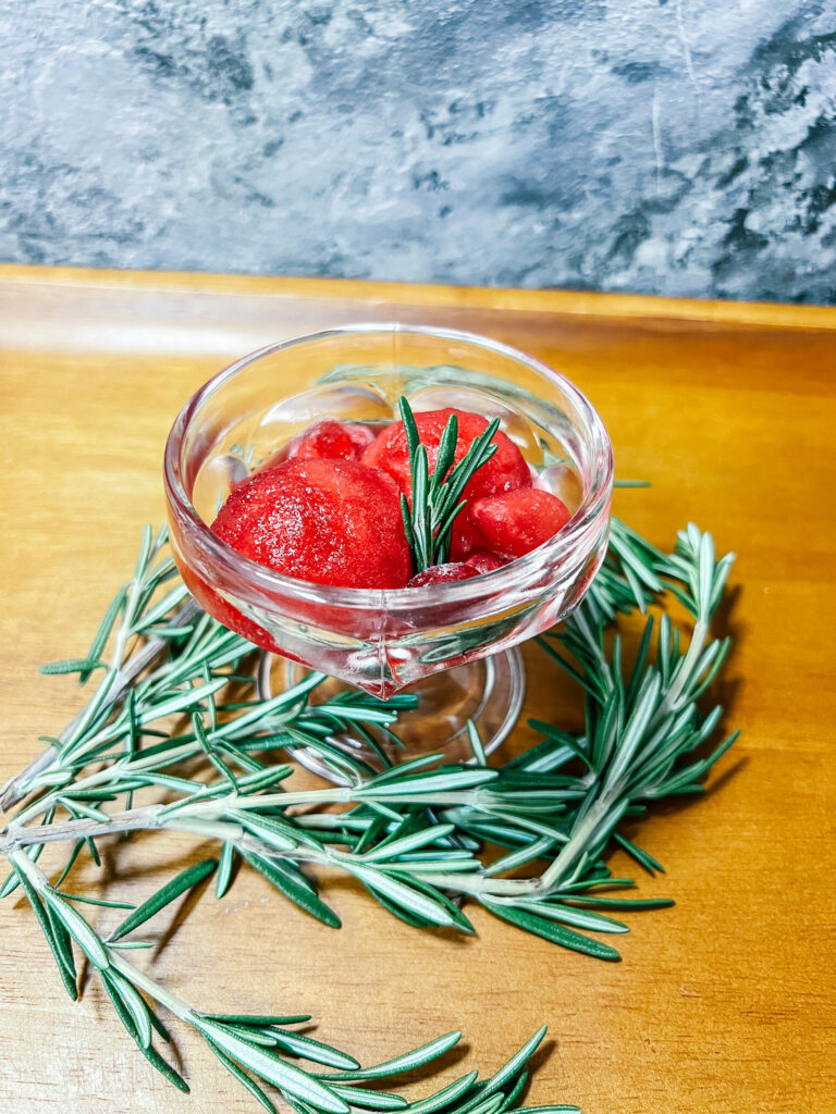 Finished Cranberry Granita in a small dish with rosemary.