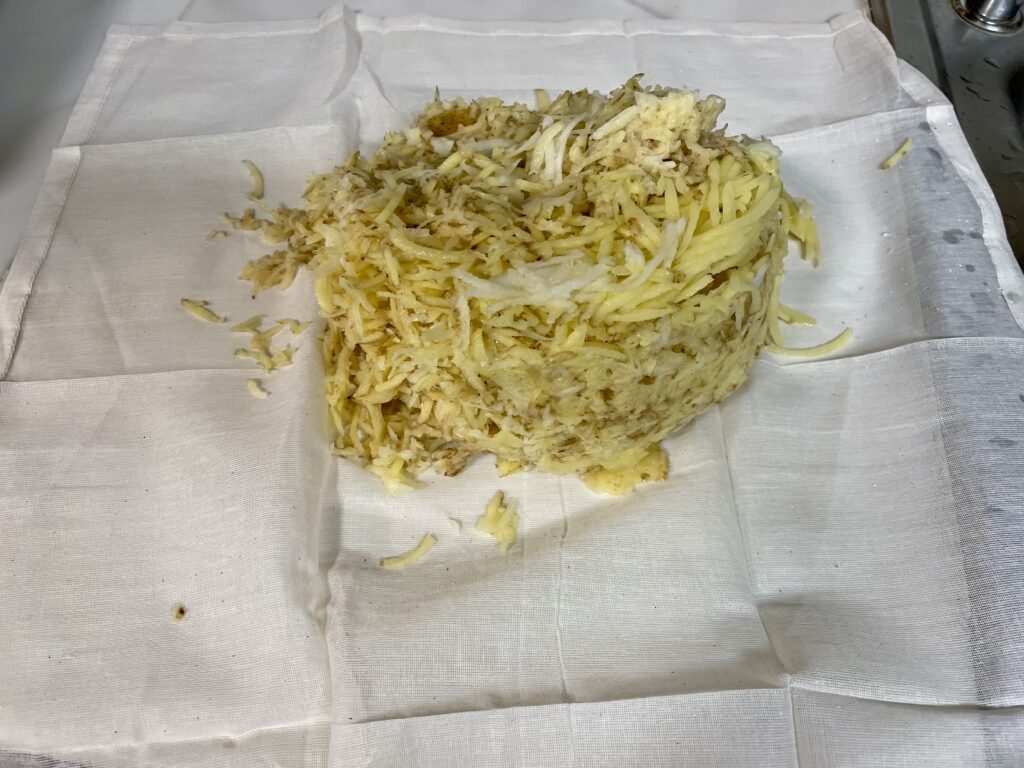 Image of shredded potato and onion on a cheese cloth.