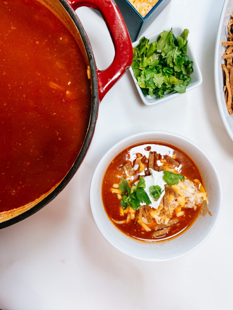 Tortilla Soup with all the toppings in a bowl next to the big pot of soup.