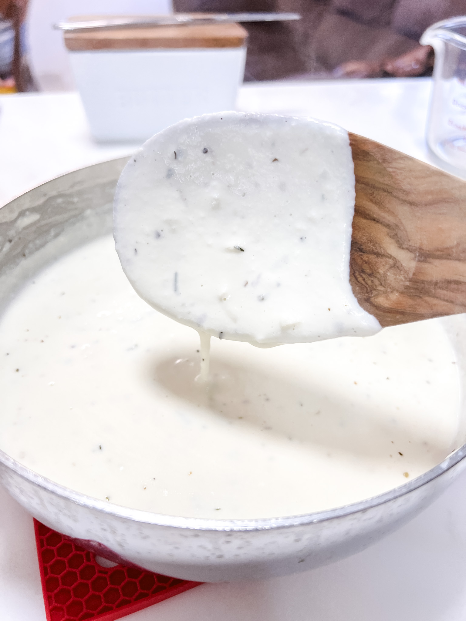 Ricotta Alfredo on a wooden spoon slowly drizzling back into the sauce pan.