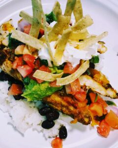 a white plate topped with chicken, rice, and black beans