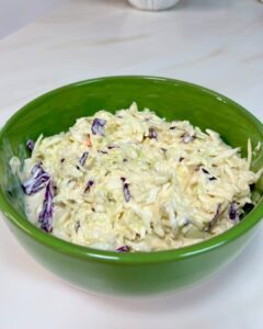 a bowl of coleslaw sitting on top of a counter