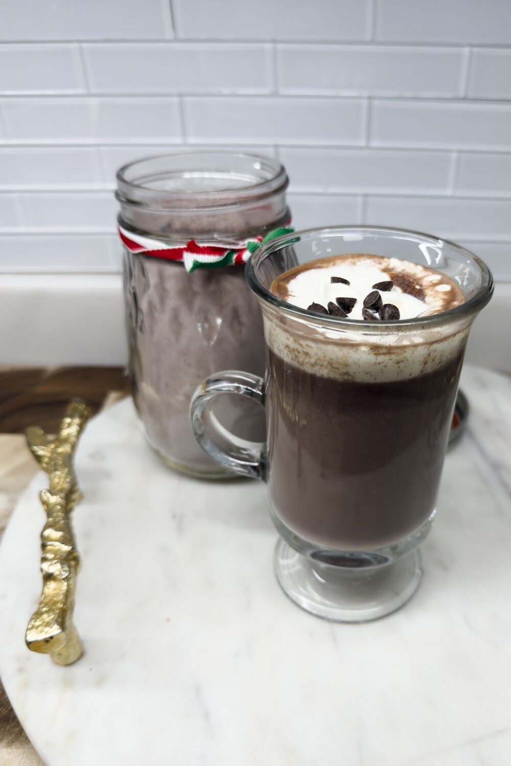 a cup of hot chocolate with whipped cream and hot chocolate mix in a mason jar