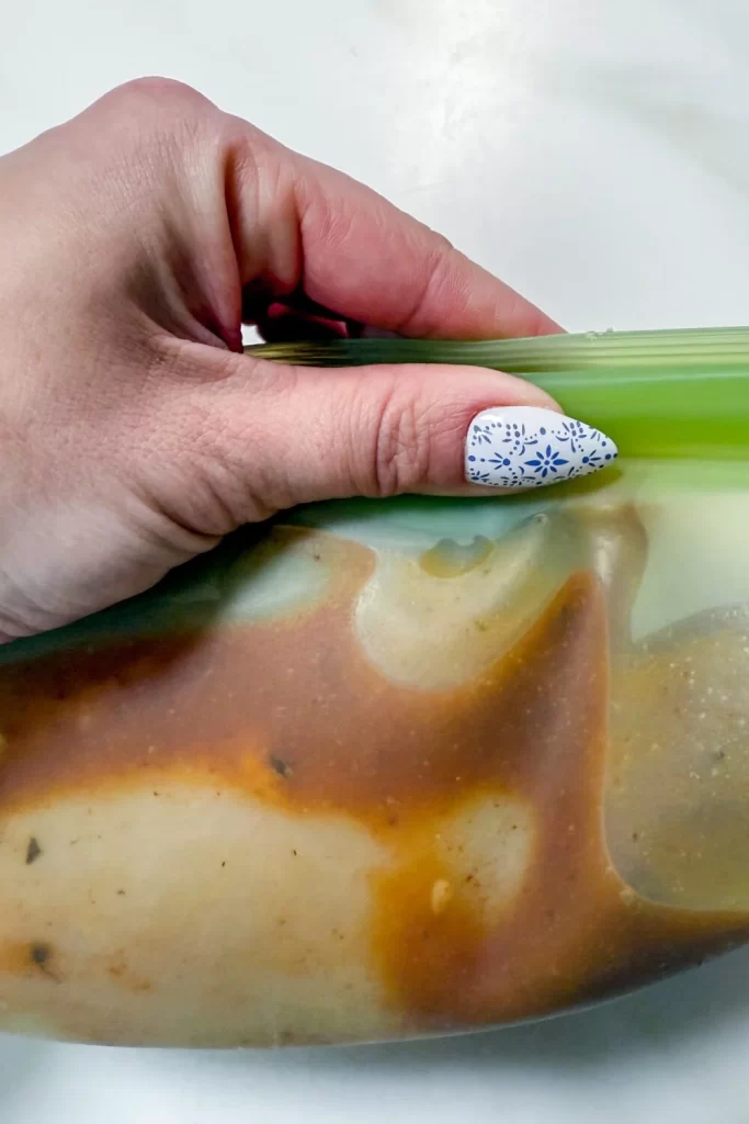 Marinade being poured over chicken in a bag 2